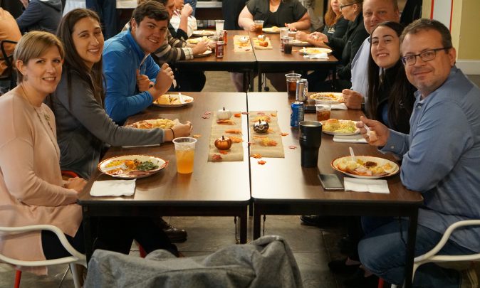 TCC Team Members smile as they enjoy a Thanksgiving potluck meal