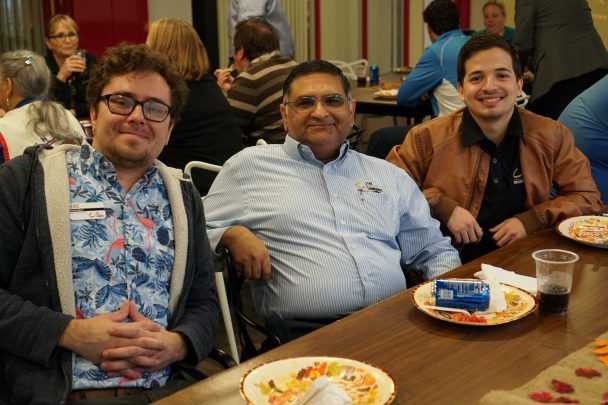 TCC Team Members smile as they enjoy a Thanksgiving potluck meal