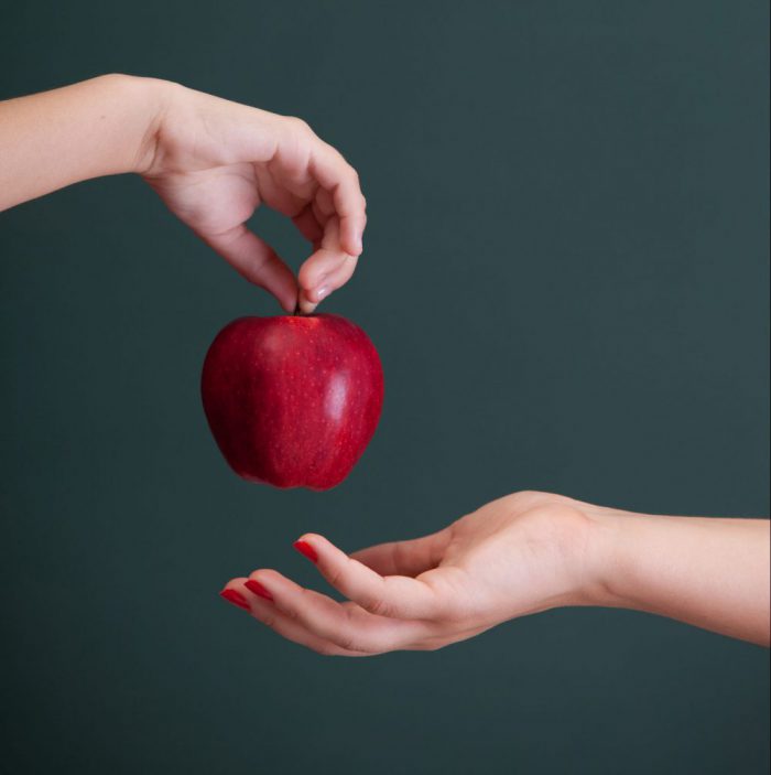 Little student hand giving apple to teacher