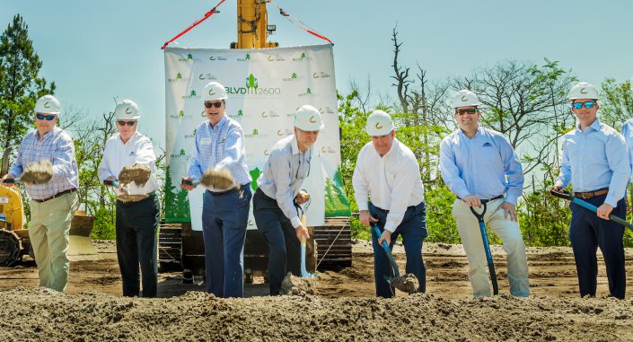 Several men standing in front of bulldozer with shovels.